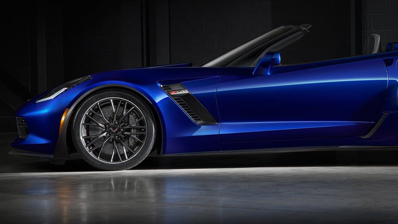 Side view of a sleek, dark blue convertible sports car with its top down.