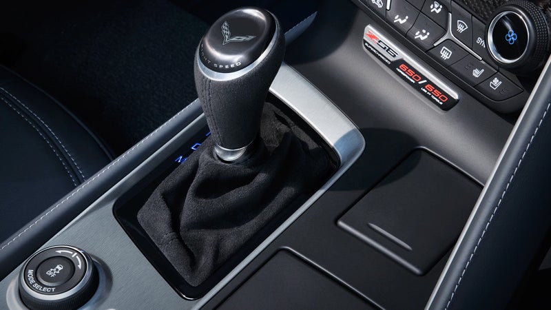 Close-up of a modern car's interior, showing a black gear shifter, center console, and dashboard controls.