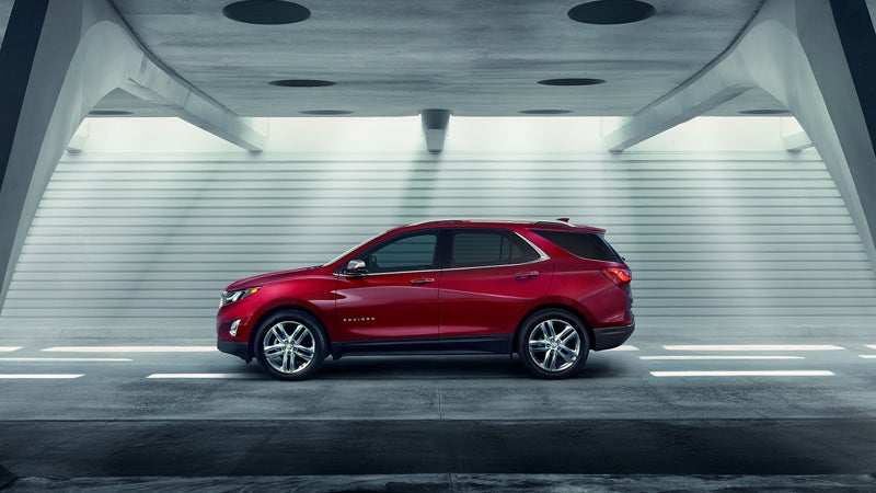 Red Chevrolet Equinox SUV parked sideways in a modern concrete tunnel or garage with ribbed walls.