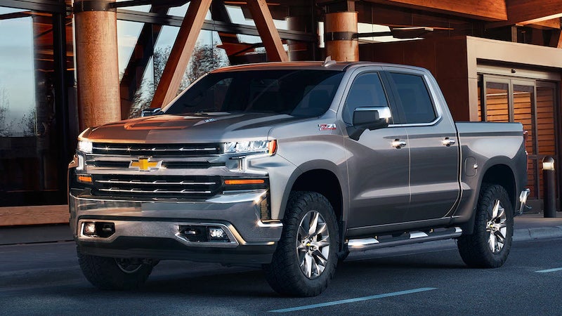 Gray Chevrolet Silverado Z71 pickup truck parked on asphalt in front of a modern building with large glass windows.