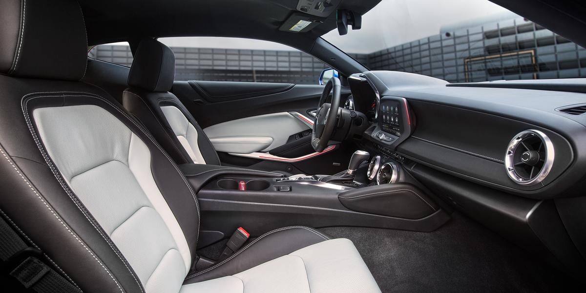 Driver's side interior of a car with black and white leather seats, steering wheel, and dashboard.