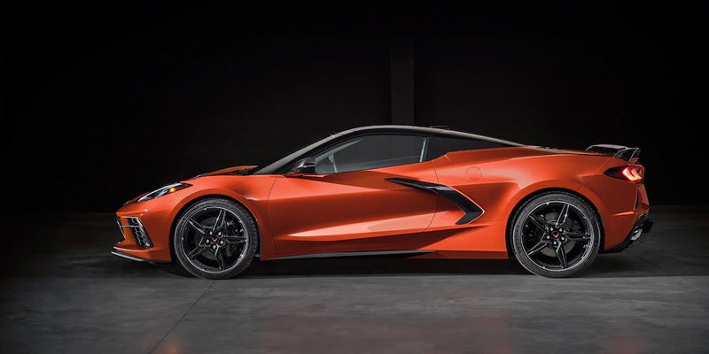 Amplify Orange Chevrolet Corvette C8 sports car, side profile, with black roof and wheels against a dark background.