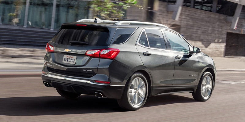 Dark grey Chevrolet Equinox SUV driving away on a road in an urban setting.