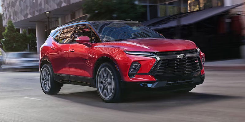 Red Chevrolet Blazer SUV driving on a city street, motion blur visible.