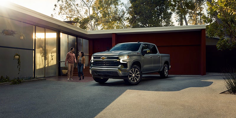 Chevrolet Silverado truck parked outside a modern home as a couple walks past its front.