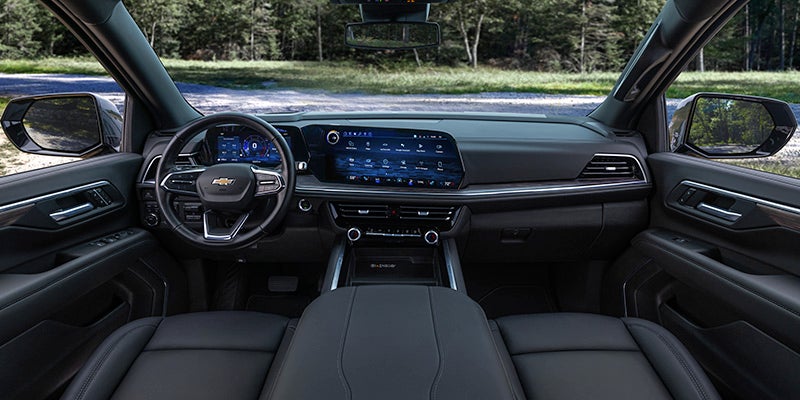 View from inside a modern Chevrolet car interior showing the dashboard, steering wheel, digital screens, and natural outdoor scenery.