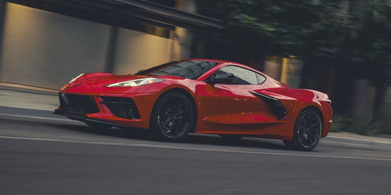 Red sports car driving on a city street, captured with motion blur to emphasize speed and performance