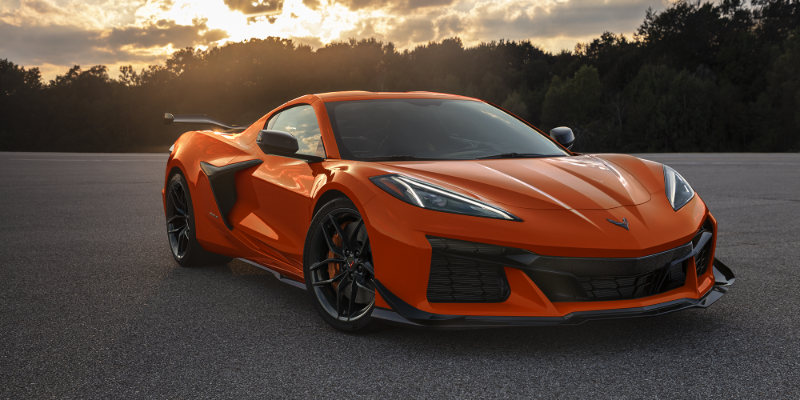 Orange Chevrolet Corvette coupe parked outdoors with a scenic sunset backdrop