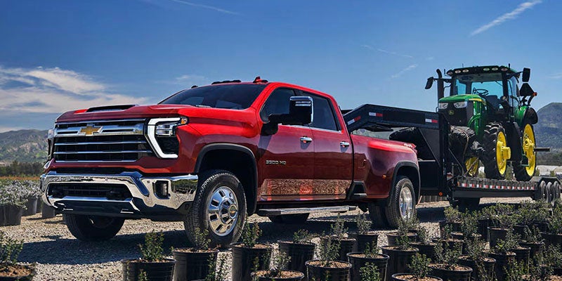 Chevrolet Silverado HD truck towing trailer with tractor.