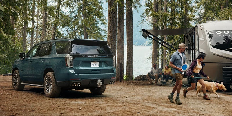 Chevrolet Tahoe SUV parked at forest campsite.