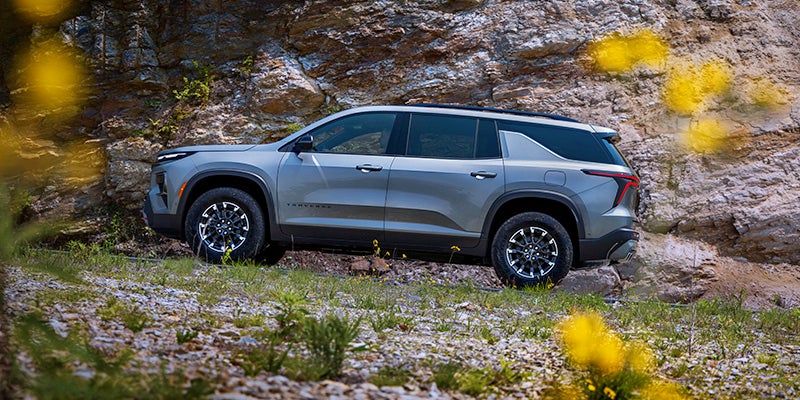 Side view of Chevrolet Traverse parked near rocky terrain
