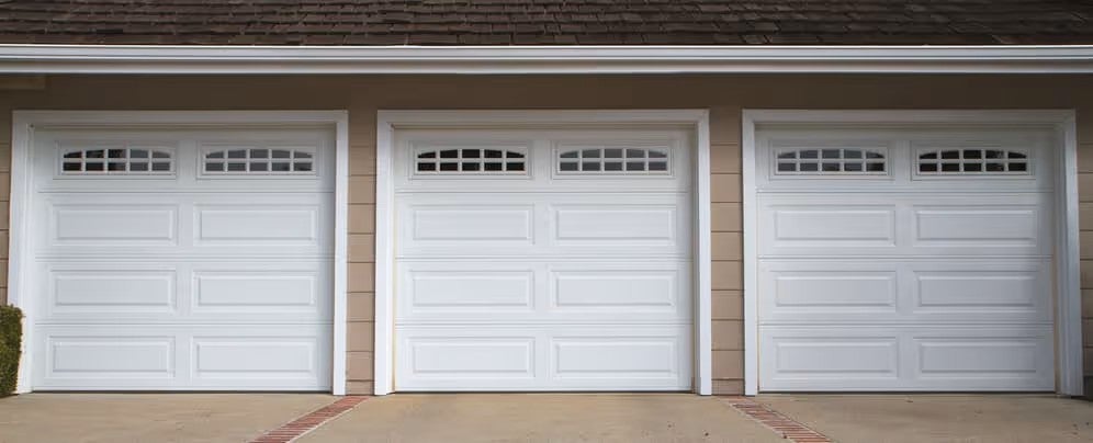 Three white residential garage doors on a home exterior